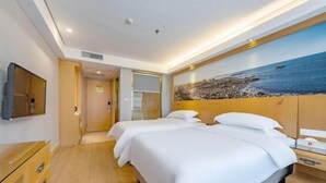 A hotel room with two beds, a large painting of a beach, a wooden dresser, and a television on the wall. - GreenTree Eastern Hotel(Shenzhen Jingtian Metro Station Store) (Shenzhen)