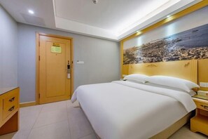 A hotel room with a large bed, a wooden headboard, a nightstand, and a door with a sign. - GreenTree Eastern Hotel(Shenzhen Jingtian Metro Station Store) (Shenzhen)