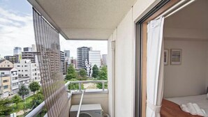 A balcony with a view of the city, a bed with a wooden headboard, and an air conditioning unit. - Daikoku Apartment 602 - Namba Apt3 minJR Imamiya/Daikokucho St/Veranda (Osaka)