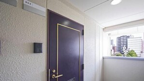 A door with a number plate, a small vent, and a window with a view of buildings. - Daikoku Apartment 602 - Namba Apt3 minJR Imamiya/Daikokucho St/Veranda (Osaka)