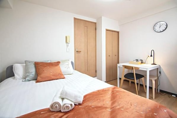 Un dormitorio con cama, escritorio y silla.