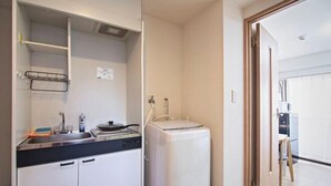 A compact kitchen with a built-in dishwasher, a small sink, and a countertop with a kettle. - Daikoku Apartment 602 - Namba Apt3 minJR Imamiya/Daikokucho St/Veranda (Osaka)