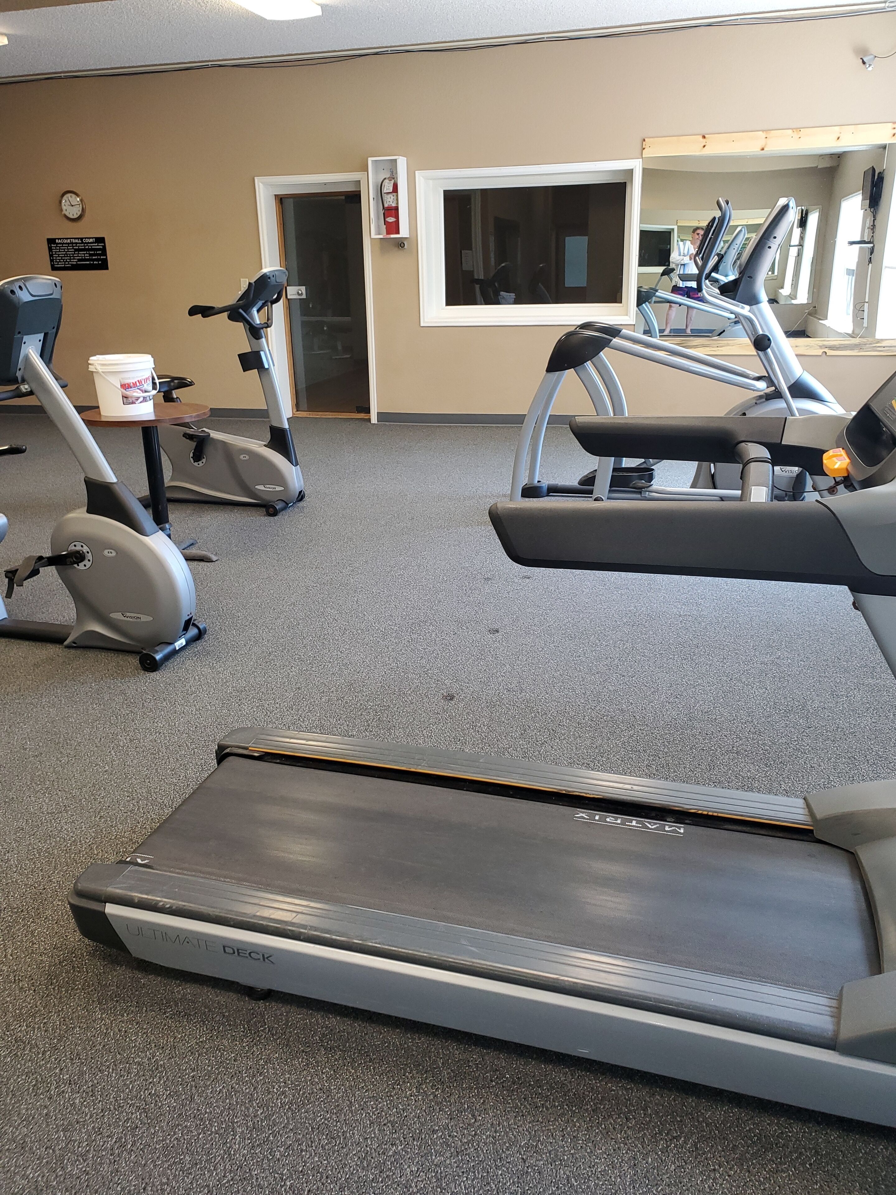 Une salle de sport équipée de tapis de course, de vélos elliptiques et d’un mur recouvert de miroirs.