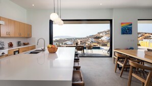 Une cuisine moderne dotée d’un grand îlot central, de meubles en bois et offrant une vue sur une ville côtière.