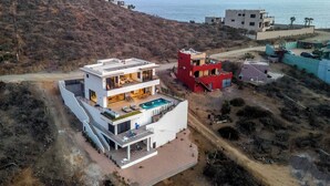 Une maison moderne à deux étages avec piscine, située près d’une plage et offrant une vue sur la mer.