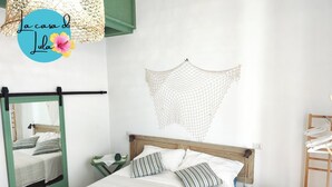 A bedroom with a bed, a hanging net, a mirror, and a wooden chair.