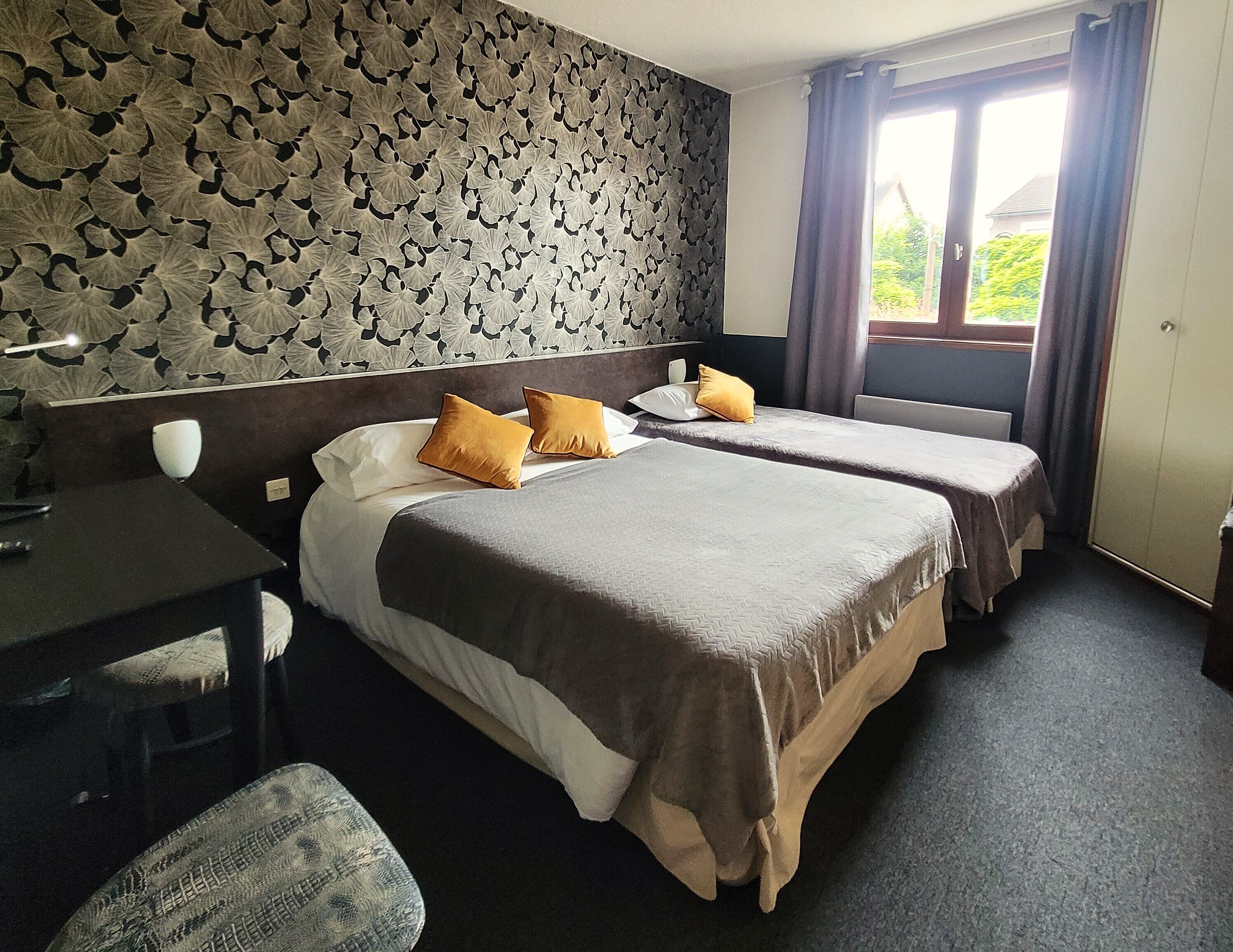 A hotel room with two beds, a desk, and a chair.