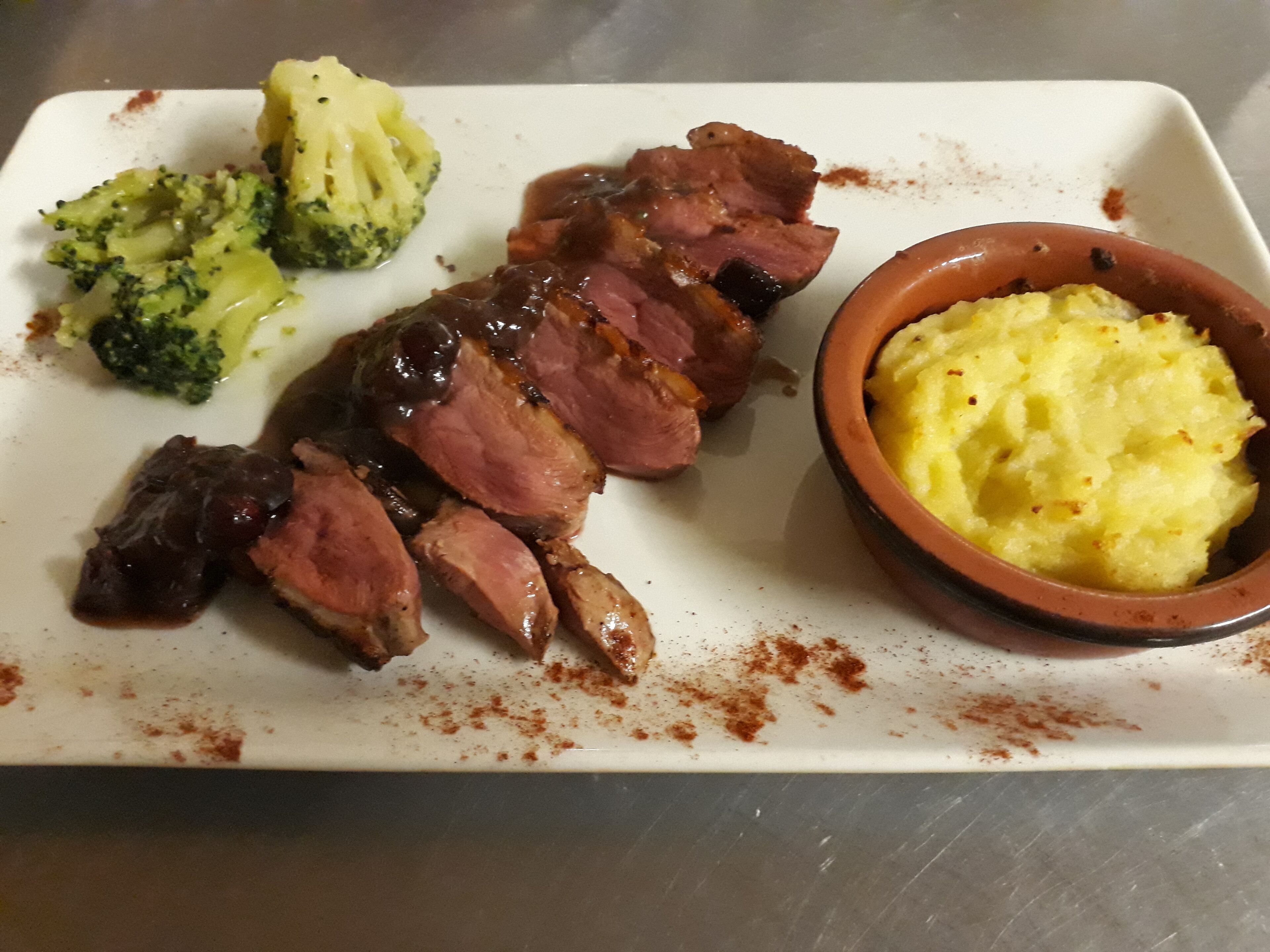 A plate with sliced meat, broccoli, and mashed potatoes.