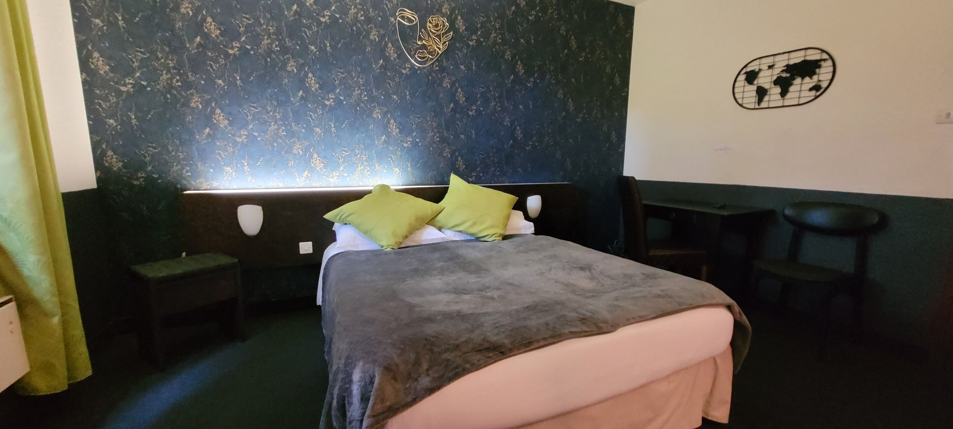 A bedroom with a bed, two nightstands, a bench, a world map decoration, and a floral design on the wall.