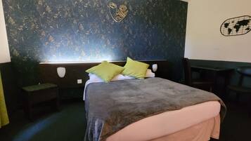 A bedroom with a bed, two nightstands, a bench, a world map decoration, and a floral design on the wall.