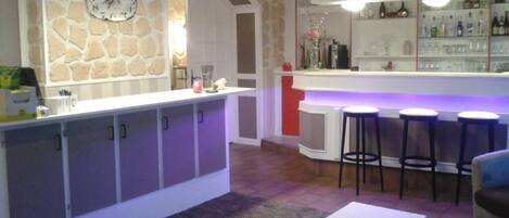 Zona de bar con taburetes, mostrador y un reloj en la pared.