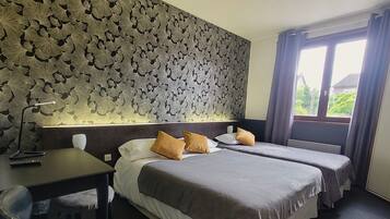 A hotel room with two beds, a desk, a chair, and a patterned wall.