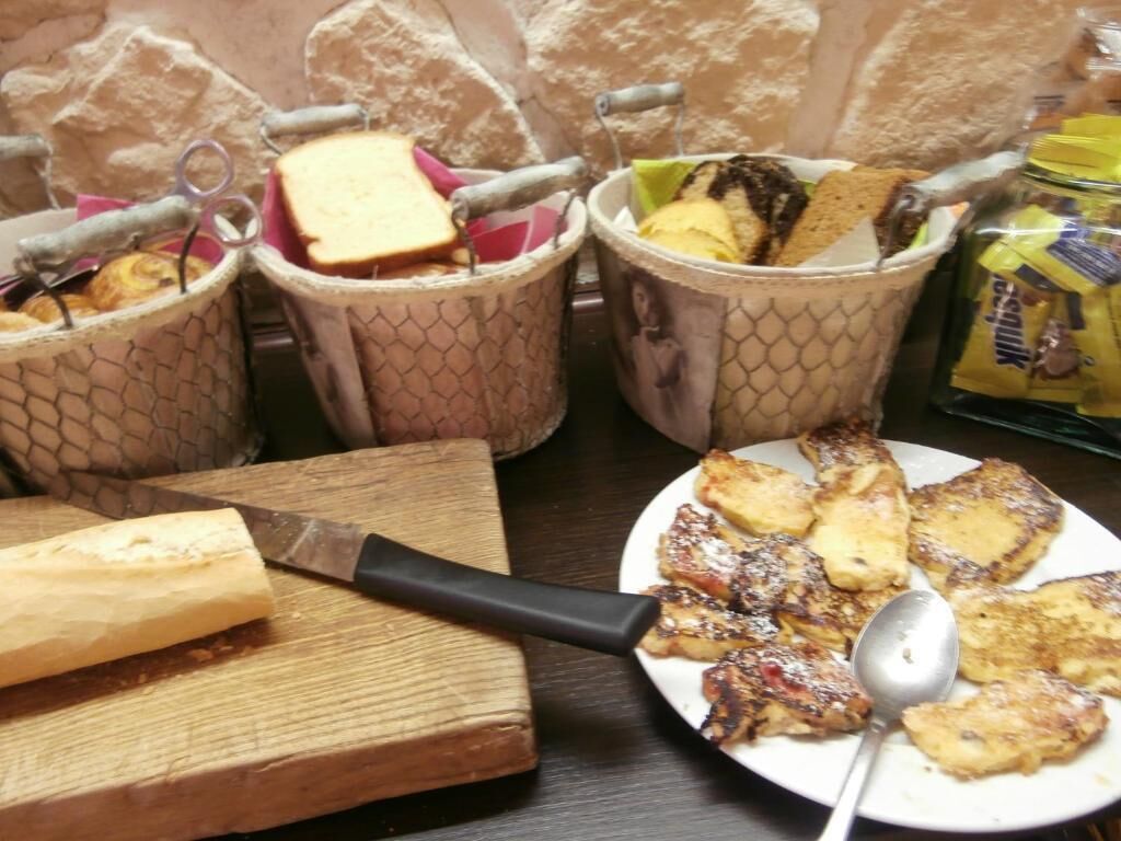 A table with food items, including a plate of toast, a knife, and containers with food.
