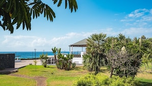 A coastal view with a restaurant, a stone wall, and a pathway leading to the beach.