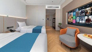 Camera d'albergo con due letti, una parete con la televisione, una scrivania e una sedia.