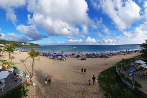 Une plage avec des parasols, des gens et une vue sur l’océan.