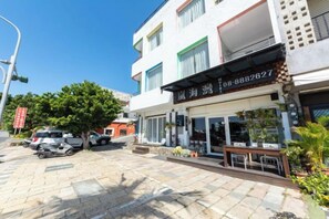 Un hotel con vetrina, posti a sedere all'aperto e un'area di parcheggio.