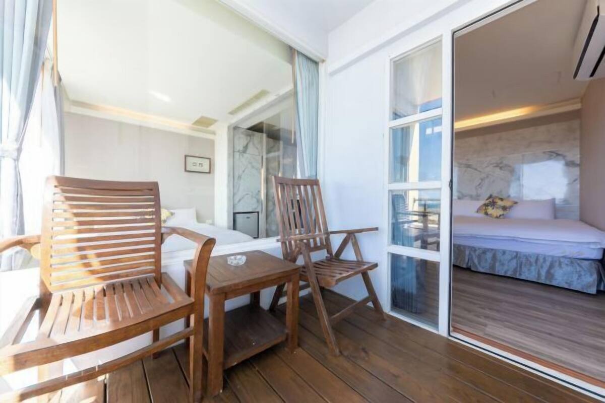 A room with a bed, a wooden table, and two wooden chairs.