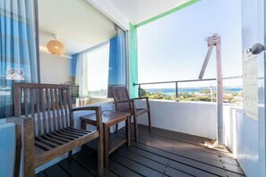 Un balcon avec des chaises en bois, une table et une vue sur la mer.