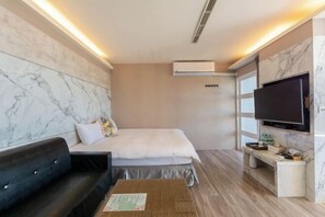 Une chambre d’hôtel équipée d’un lit, d’un canapé, d’une télévision et d’un appareil de climatisation.