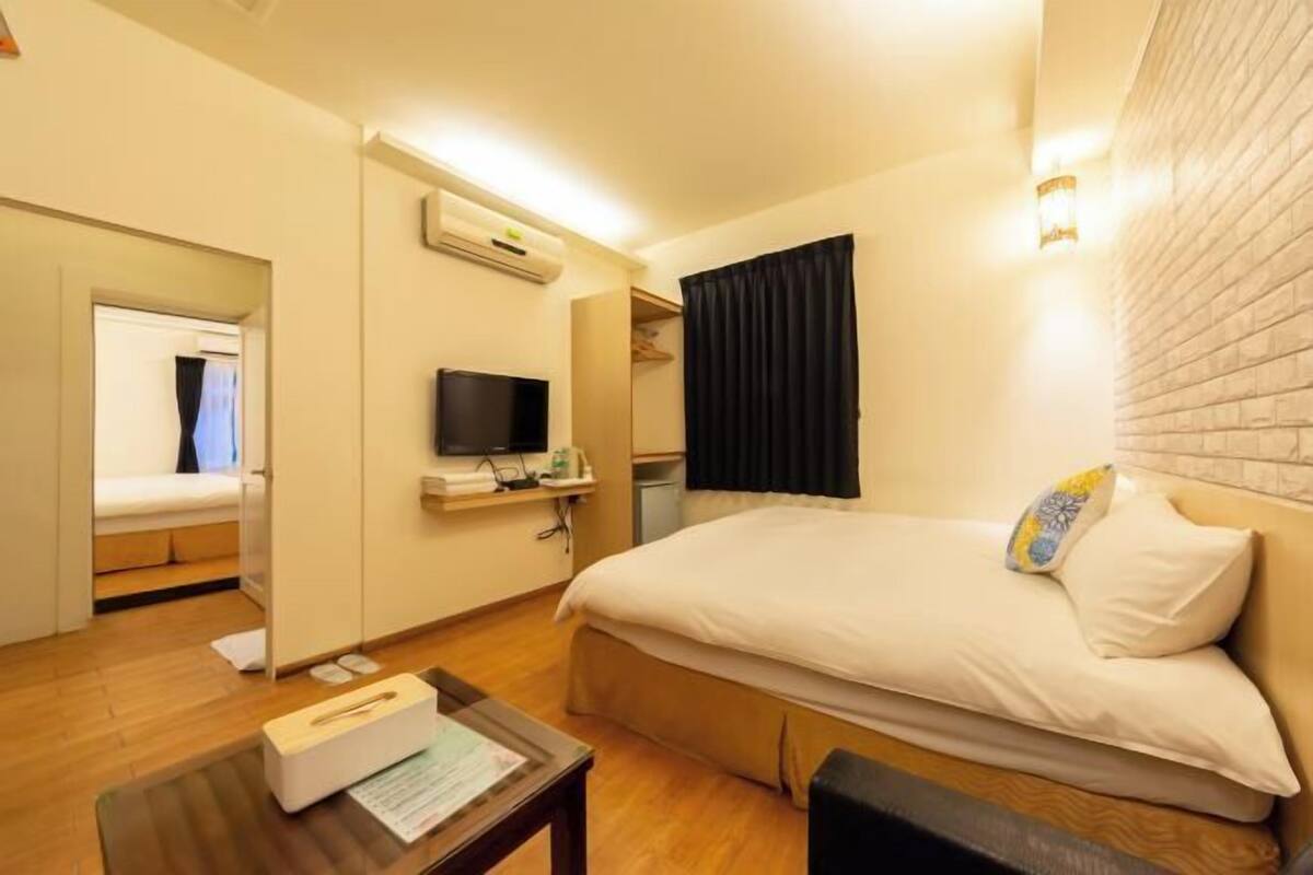 A hotel room with a bed, a TV, a desk, and a mirror.