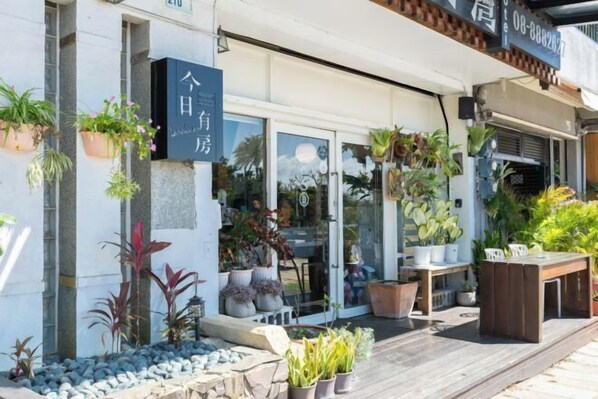 L’entrée d’un hôtel, avec un panneau indicateur, des plantes en pot et une terrasse en bois.