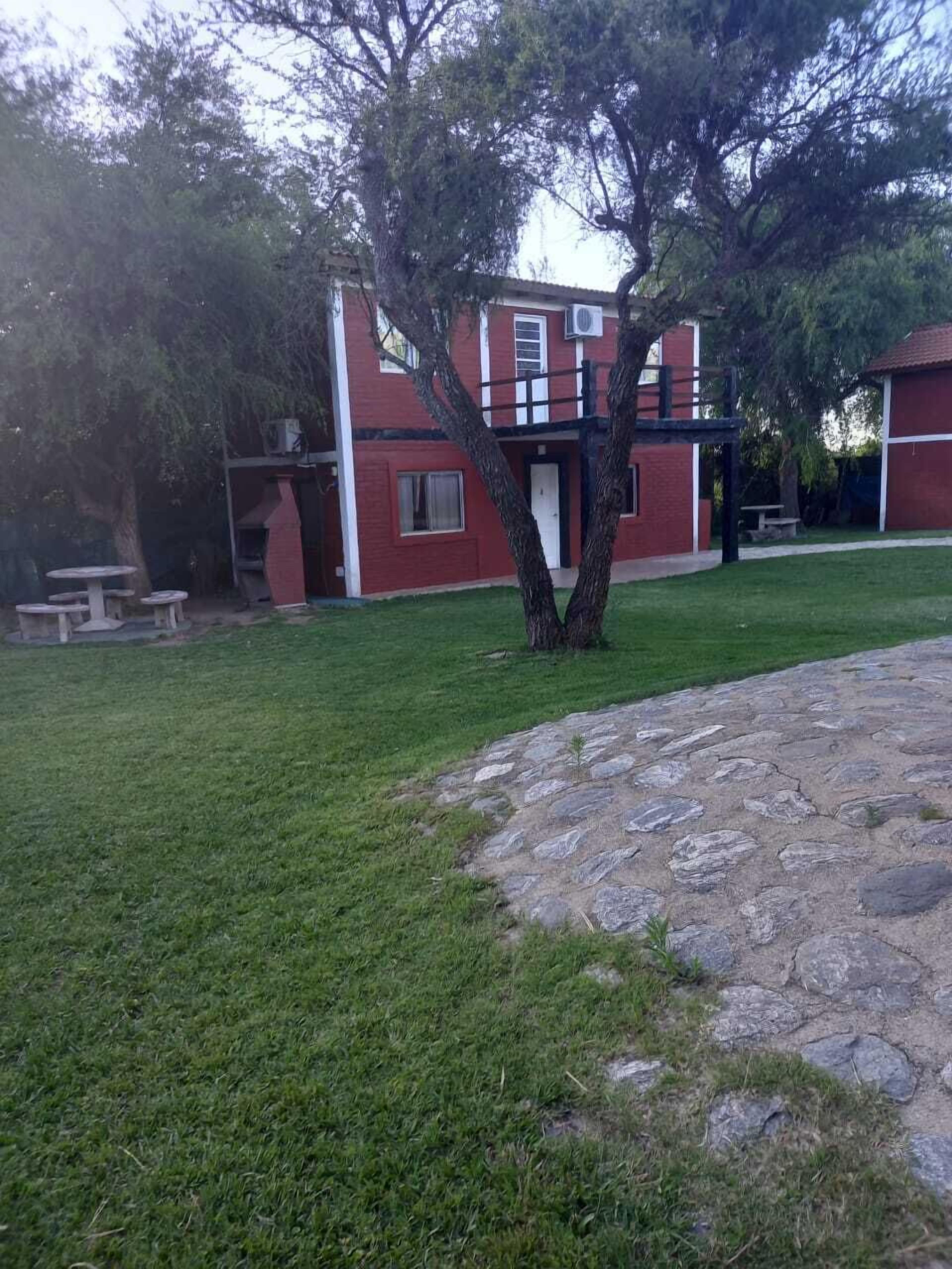 Um edifício de tijolos vermelhos com um pátio de pedra e uma árvore em primeiro plano.