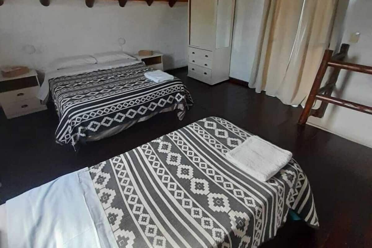Une chambre avec deux lits, une armoire, un miroir et une échelle en bois.