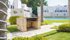 Un espace extérieur moderne comprenant un barbecue, une piscine et un mur en pierre.