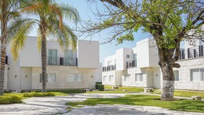 Un bâtiment moderne au design épuré et minimaliste, doté d’une cour intérieure avec un chemin pavé et de la verdure.