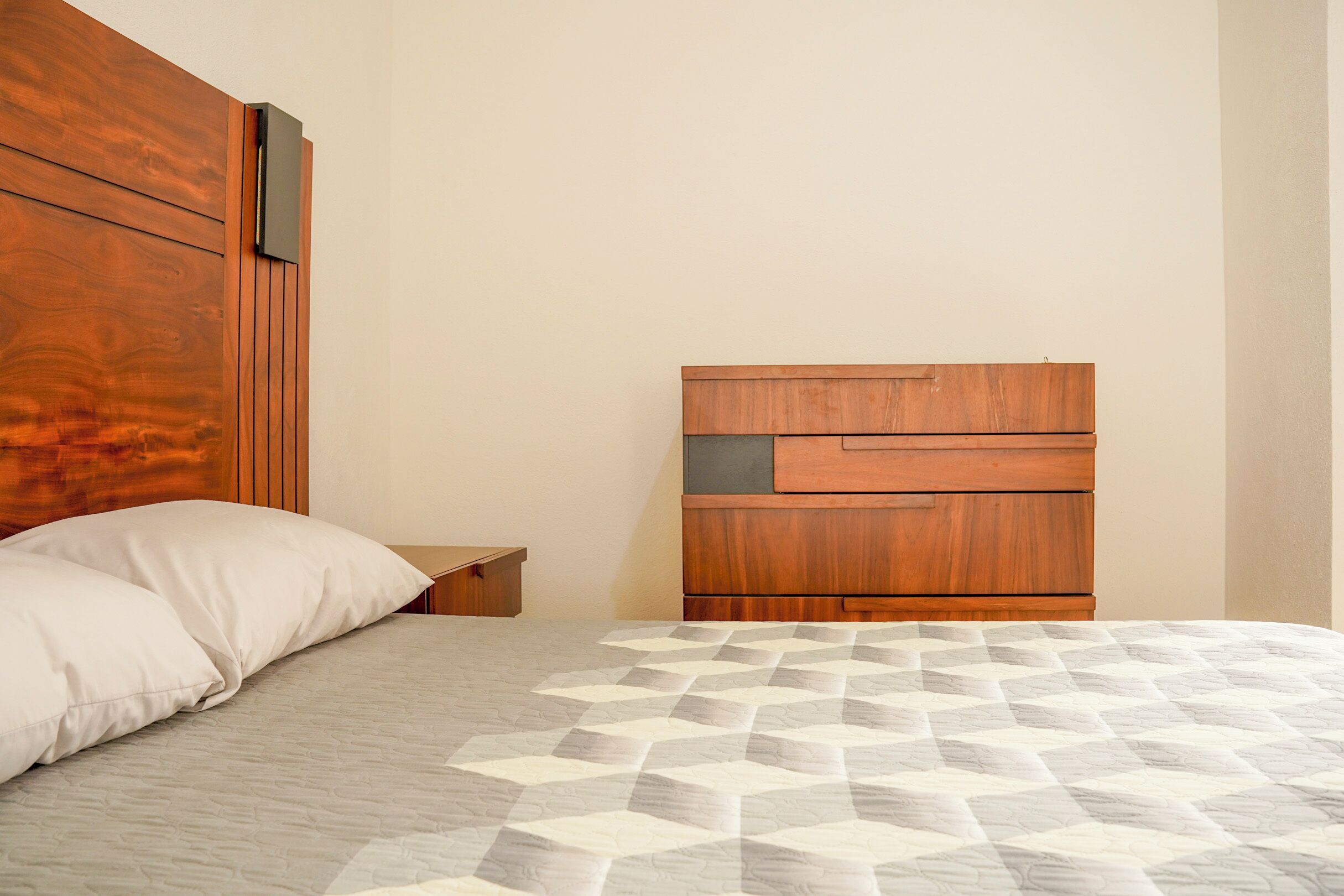 Una camera da letto con una testiera in legno, un comodino e un letto con copripiumino fantasia.