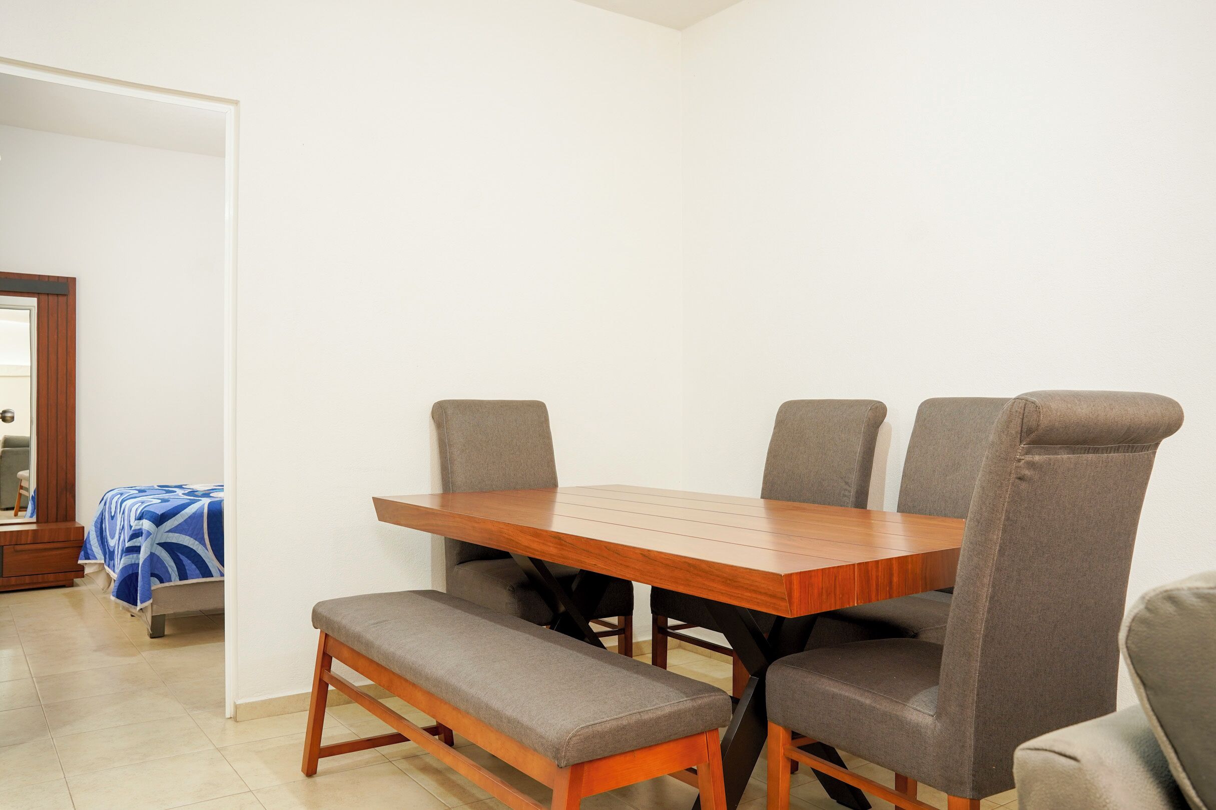 A dining area with a wooden table and four grey upholstered chairs.