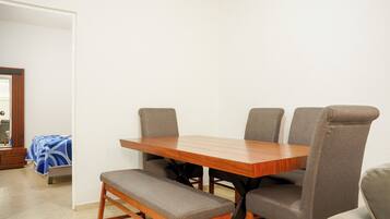 A dining area with a wooden table and four grey upholstered chairs.