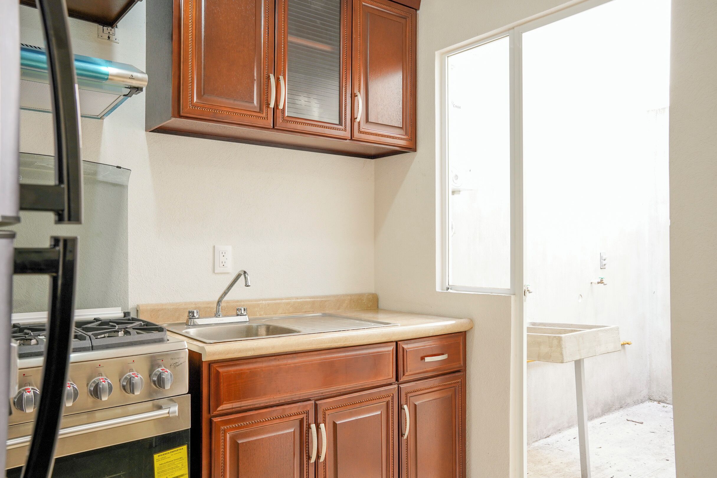 A kitchen with wooden cabinets, a stainless steel sink, and a built-in oven.