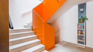 A staircase with white steps and an orange accent wall. - VIVENTE 3B BY CANARIAS GETAWAY (Las Palmas de Gran Canaria)