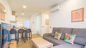 A modern living room with a grey sofa, two floral cushions, a wooden coffee table, and a TV on a stand. - VIVENTE 3C BY CANARIAS GETAWAY (Las Palmas de Gran Canaria)