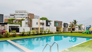 A modern residential complex with a swimming pool, greenery, and a children's play area. - Beautiful apartment near the beach (Boca del Rio)