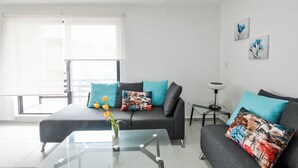 A modern living room with a sofa, a glass coffee table, and a small side table. - Beautiful apartment near the beach (Boca del Rio)