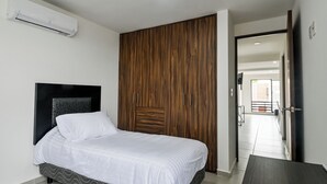 A bedroom with a bed, a wooden wardrobe, and a white air conditioning unit on the wall. - Beautiful apartment near the beach (Boca del Rio)