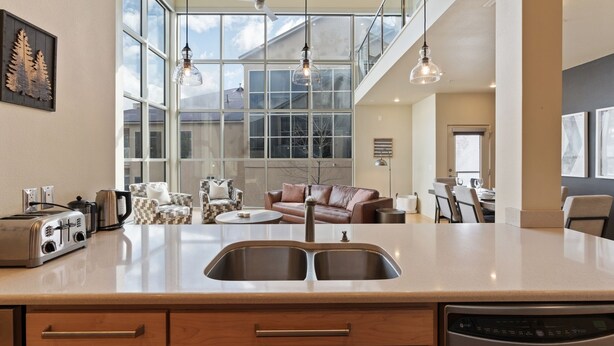 A modern kitchen with a large island, double sink, and a dining area with a sofa and chairs. - 3min Walk to Ski Lifts*Hot Tub*Sauna*Views (Brian Head)