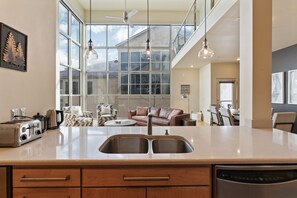 A modern kitchen with a large island, double sink, and a dining area with a sofa and chairs.