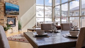 A dining area with a fireplace, a large window with a snowy mountain view, and a television mounted on the wall. - 3min Walk to Ski Lifts*Hot Tub*Sauna*Views (Brian Head)