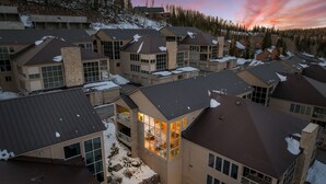 A residential area with multiple houses, some with snow on the roofs, and a prominent house with large windows and a lit interior. - 3min Walk to Ski Lifts*Hot Tub*Sauna*Views (Brian Head)