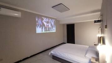 A hotel room with a bed, a wall-mounted projector, and a light fixture.