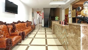 A lobby with a checkered floor, a leather sofa, a reception desk, and a wall-mounted TV. - OYO Jingbian County Tianli Holiday Hotel (Jingbian County)
