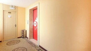 A hallway with a beige carpet, a door labeled "E01", and a red door with a logo. - OYO Jingbian County Tianli Holiday Hotel (Jingbian County)