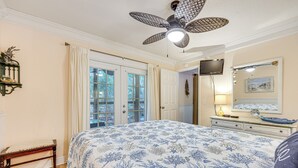 A bedroom with a large bed, a ceiling fan, a dresser, and a TV on the wall. - Fernandina Beach Condo w/ Pool + Path to Beach! (Fernandina Beach)