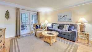 A living room with a sofa, armchairs, a coffee table, and a lamp. - Fernandina Beach Condo w/ Pool + Path to Beach! (Fernandina Beach)