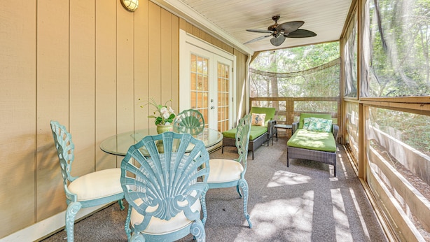A covered porch with a glass table, chairs, and a bed. - Fernandina Beach Condo w/ Pool + Path to Beach! (Fernandina Beach)