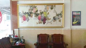 A room with a large framed painting of grapes, a wooden table, and two wooden chairs. - Wonton Hotel Yangshuo (Yangshuo)